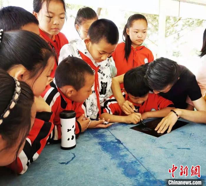 圖為朱增平(右一)教學(xué)生創(chuàng)作鍥金畫。(資料圖) 受訪者供圖