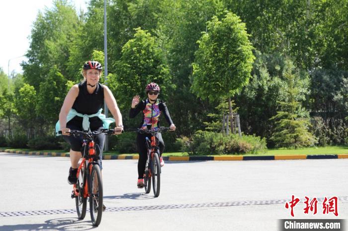 亞信副秘書長遲方(右一)與聯(lián)合國駐哈協(xié)調(diào)員在騎行活動中?！喰琶貢幑﹫D