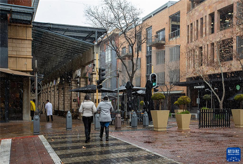 7月10日，在南非約翰內(nèi)斯堡一處商業(yè)區(qū)，人們在雪中行走。新華社記者 張譽(yù)東 攝