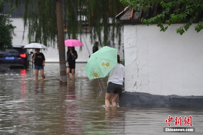 7月31日，市民行走在雨中的北京房山區(qū)瓦窯頭村。北京市氣象臺當日10時發(fā)布分區(qū)域暴雨紅色預(yù)警信號。北京市水文總站發(fā)布洪水紅色預(yù)警，預(yù)計當日12時至14時，房山區(qū)大石河流域?qū)⒊霈F(xiàn)紅色預(yù)警標準洪水。<a target='_blank' href='/'><p  align=