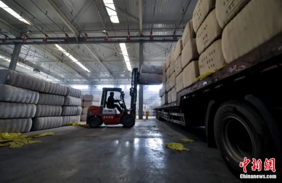 新疆喀什綜合保稅區(qū)，喀什啟路國際貿(mào)易有限公司的倉庫內(nèi)，工人正在裝載從塔吉克斯坦和烏茲別克斯坦進口的棉花。劉新攝