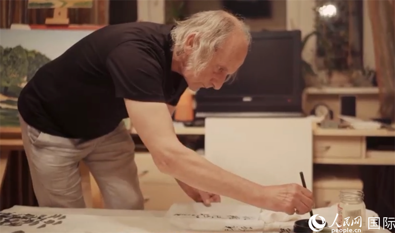 伊戈爾·布爾東諾夫在畫作上題詞。人民網(wǎng)記者 馬天翼攝