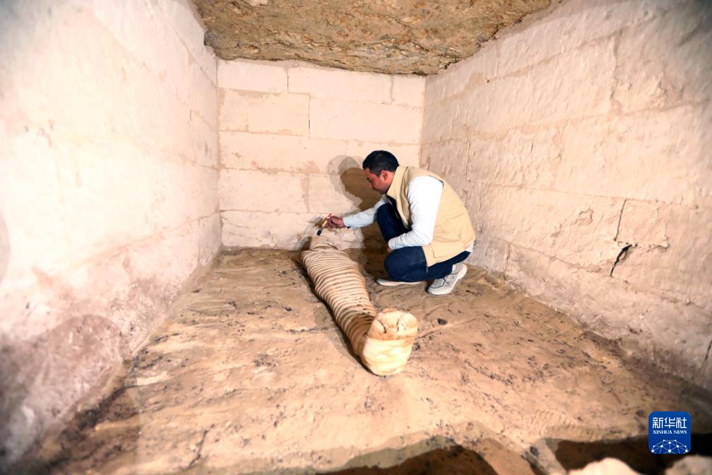 10月15日，在埃及明亞省考古現(xiàn)場，考古人員清理一座石鑿墓中的木乃伊。新華社發(fā)（艾哈邁德·戈馬攝）