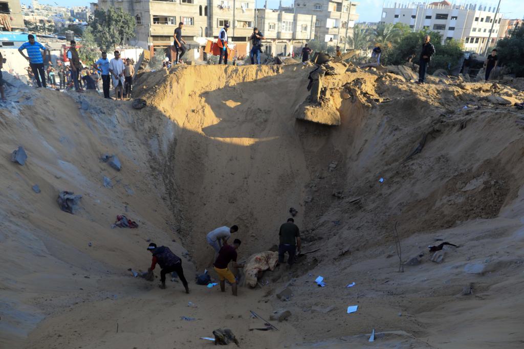 10月16日，在加沙地帶南部城市汗尤尼斯，人們在遭以色列襲擊后的建筑廢墟中救援傷者。 新華社發(fā)（亞西爾·庫迪 攝）