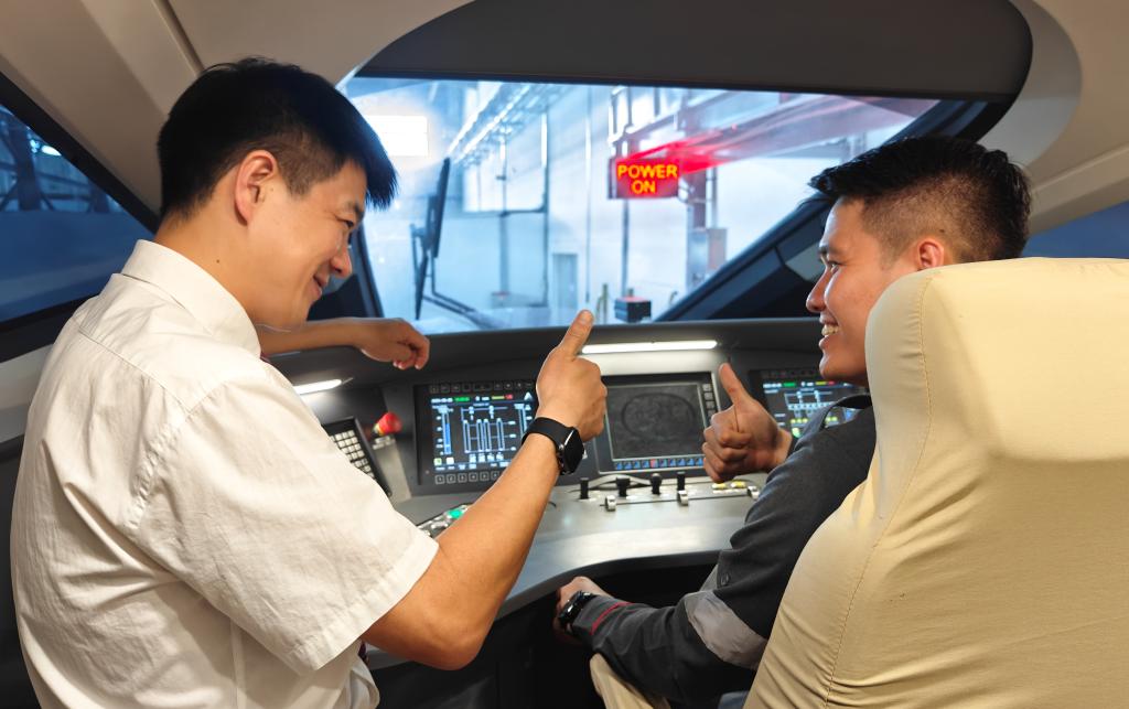 8月25日，在印度尼西亞萬隆的雅萬高鐵德卡魯爾動車所內(nèi)，中國師傅穆振（左）在向印尼火車司機塞蒂亞萬講解動車組出庫前的上電作業(yè)。