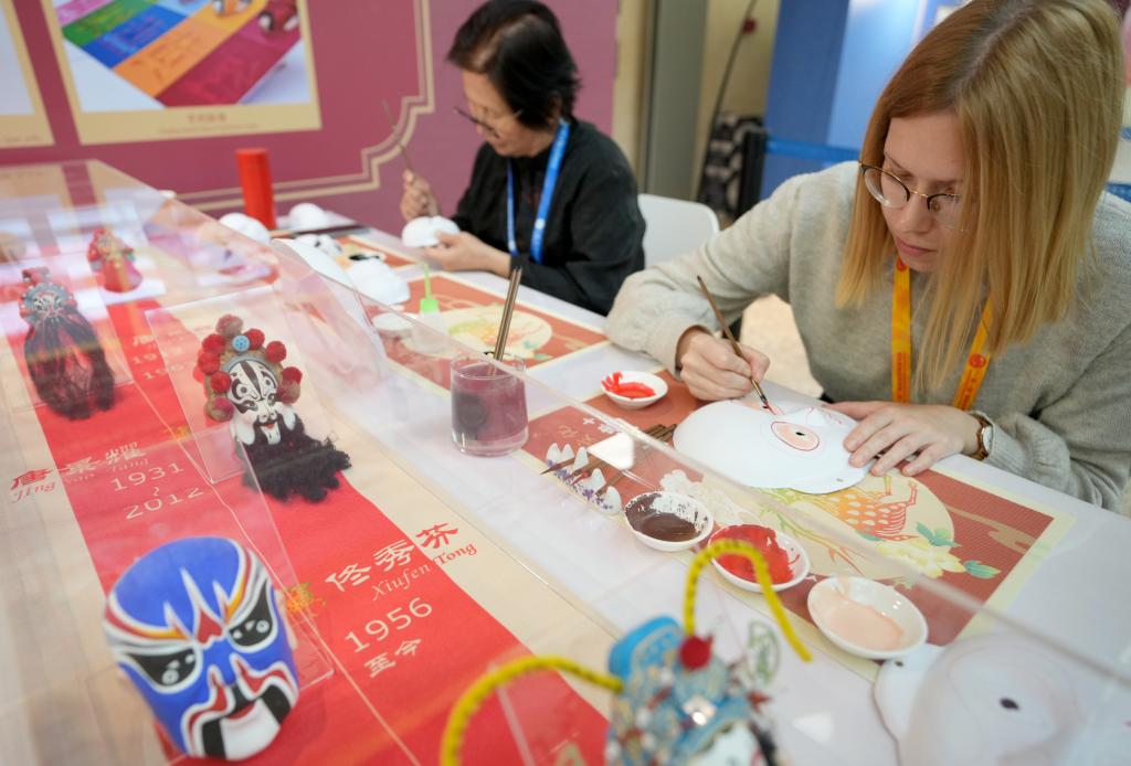 10月16日，在第三屆“一帶一路”國際合作高峰論壇新聞中心，來自比利時的記者（右）體驗畫京劇臉譜。新華社記者 王毓國 攝