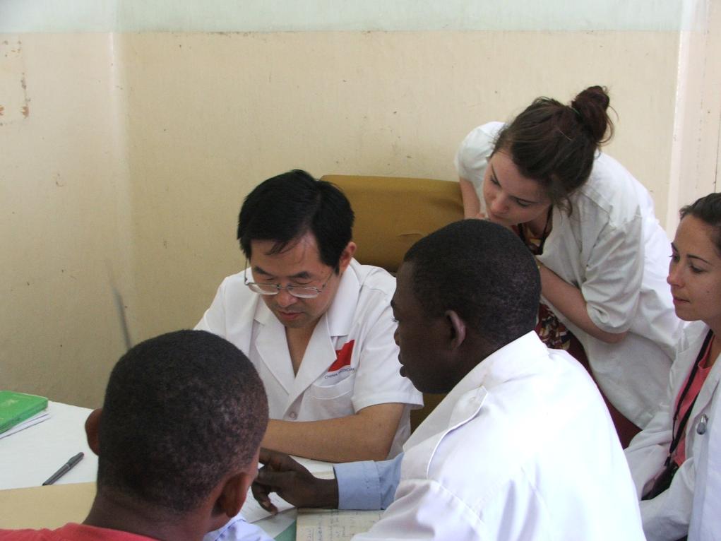 2011年7月22日，在坦桑尼亞桑給巴爾納茲莫加醫(yī)院外科門診，中國(guó)第24批援桑給巴爾醫(yī)療隊(duì)隊(duì)長(zhǎng)盧建林為當(dāng)?shù)鼗颊咴\治并帶教實(shí)習(xí)生。新華社發(fā)（國(guó)家衛(wèi)生健康委供圖）
