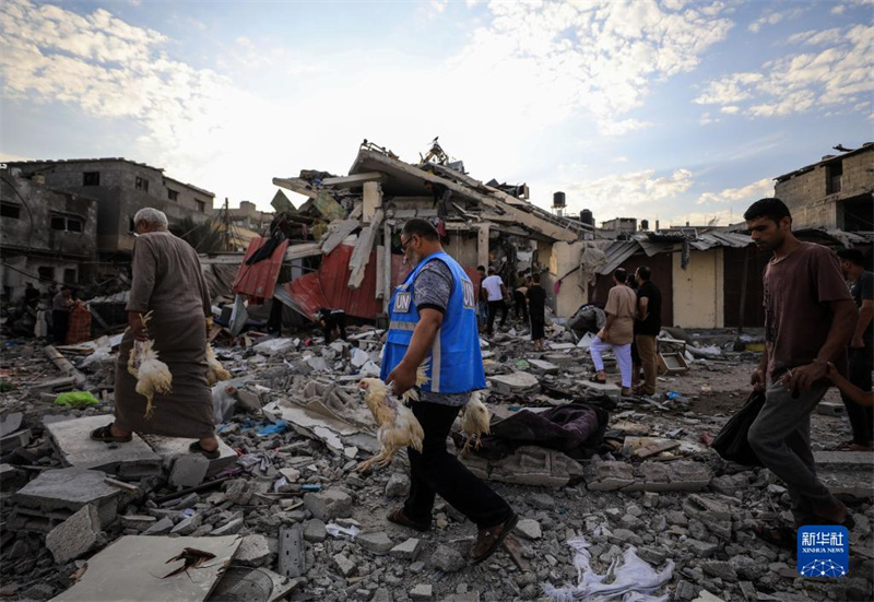 10月27日，在加沙地帶南部城市汗尤尼斯，人們經(jīng)過(guò)以軍襲擊后的房屋廢墟。