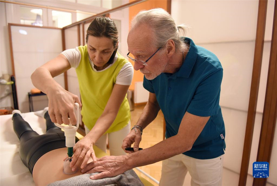 12月12日，在奧地利維也納，科格勒醫(yī)生（右）和助手在為病人進行拔罐治療。新華社記者 賀燦鈴 攝