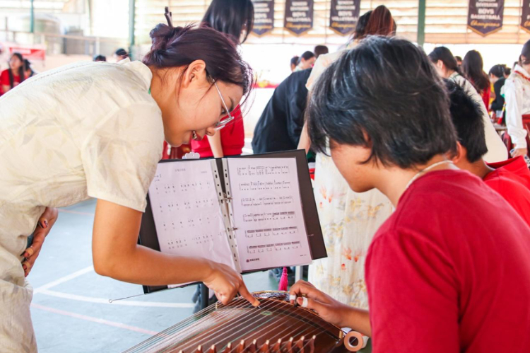 志愿者教師指導(dǎo)學(xué)生彈奏古箏?；顒又鬓k方供圖