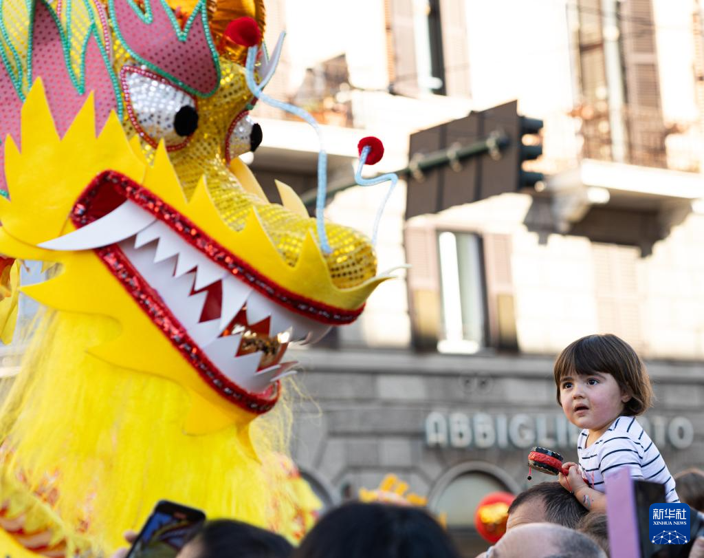 2月18日，在意大利羅馬，一名小朋友在彩妝巡游上觀(guān)看舞龍。新華社記者 李京 攝