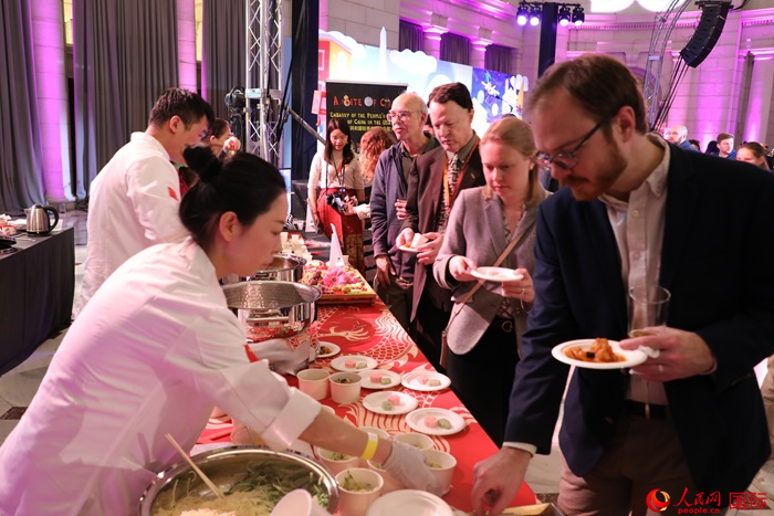 當(dāng)?shù)貢r(shí)間3月7日晚，華盛頓聯(lián)合車站廣場舉行駐美使團(tuán)“使館主廚挑戰(zhàn)賽”。圖為當(dāng)?shù)孛癖娫谥袊古_前體驗(yàn)中國美食。人民網(wǎng)記者 李志偉攝