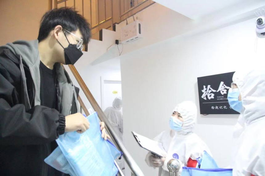 社區(qū)工作人員和志愿者身穿防護(hù)服上門送馬應(yīng)龍大健康防疫包。徐帥攝