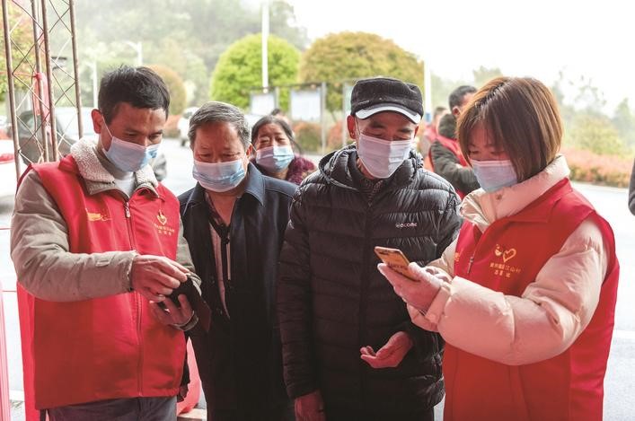 長(zhǎng)沙縣黨員志愿者正在幫助參與核酸檢測(cè)的群眾掃描“場(chǎng)所碼”。劉思源 攝