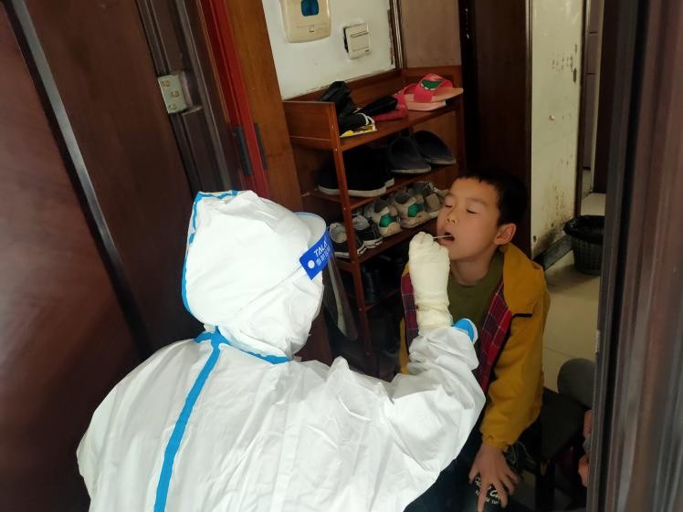 醫(yī)務(wù)工作者為封控區(qū)的居民上門采樣核酸。單位供圖