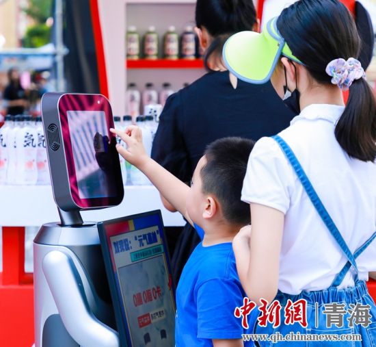 圖為一名小朋友正在和機(jī)器人“志愿者”進(jìn)行互動(dòng)。 沐聞 攝