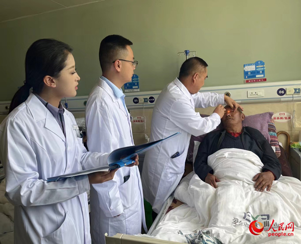 董光明（左三）帶領(lǐng)醫(yī)生對患者進(jìn)行術(shù)前檢查。人民網(wǎng)記者 杜燕飛攝