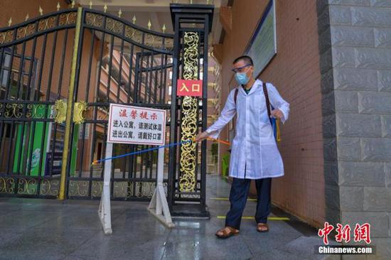 資料圖：海口經(jīng)濟學(xué)院的工作人員在學(xué)生宿舍樓入口消毒。 中新社記者 駱云飛 攝