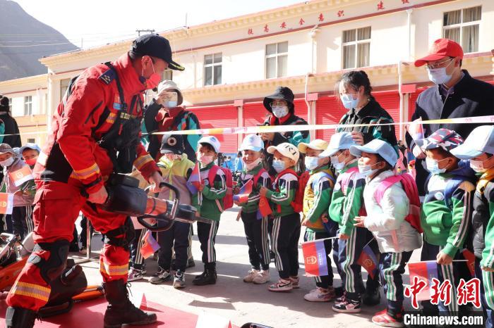 圖為消防指戰(zhàn)員為學(xué)生講解、演示先進救援裝備?！≮w琳 攝