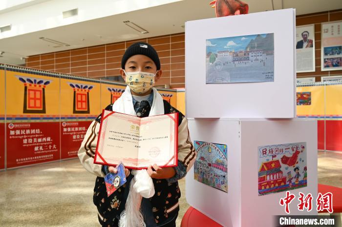 圖為一名獲獎學生與自己的繪畫作品合影。　趙朗 攝