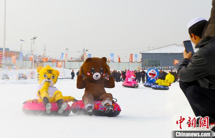 圖為臨夏市南龍鎮(zhèn)馬家莊村舉辦的鄉(xiāng)村文化旅游節(jié)上，游客穿著卡通服裝在體驗(yàn)雪上飛碟項(xiàng)目。近年來(lái)，臨夏州形成了“春賞花、夏避暑、秋摘果、冬玩雪”的全季節(jié)旅游產(chǎn)品體系。(資料圖) 高展 攝