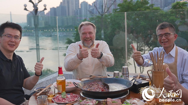 康寧顯示科技事業(yè)部全球拓建項(xiàng)目總監(jiān)軻寶華（中）和同事在重慶南濱路吃火鍋。人民網(wǎng)記者 蘇纓翔攝