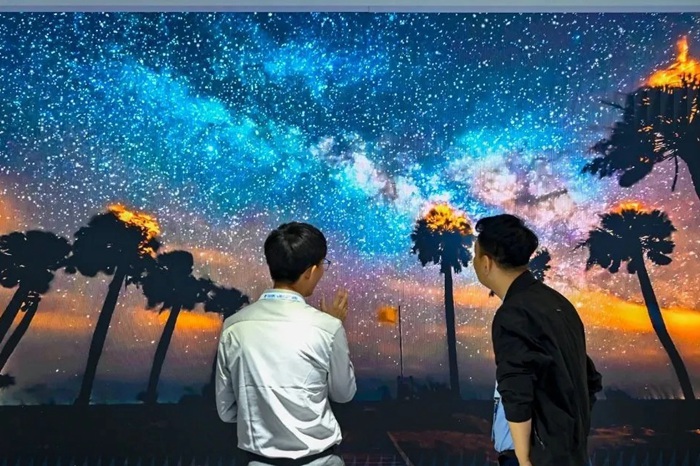 長春光博會希達(dá)電子展區(qū)，一位工作人員正在給一位觀眾講解。（長春新區(qū)供圖）