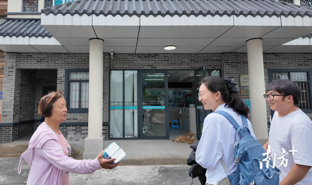 公共服務(wù)組成員王櫻潔（中）和張龍（右）在崖口村衛(wèi)生室前跟村民打招呼。