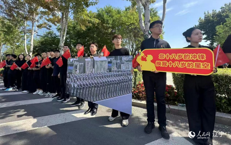 沈陽市人民廣場上，大學生們手持閱兵的圖片，告慰英烈。人民網(wǎng)記者 周頌雪攝