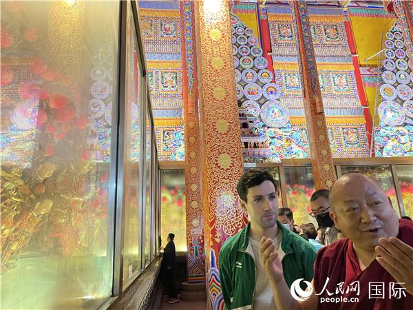 7月25日，省級非物質(zhì)文化遺產(chǎn)項目塔爾寺酥油花的代表性傳承人朋措堅參（右）在塔爾寺酥油花館講解酥油花的制作過程。人民網(wǎng) 謝瑩攝