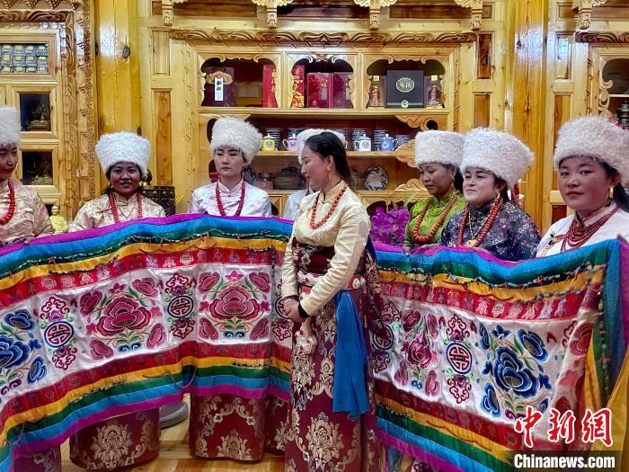 圖為女性展示村民自發(fā)繡制的“百米五彩哈達(dá)”?！±钣穹?攝