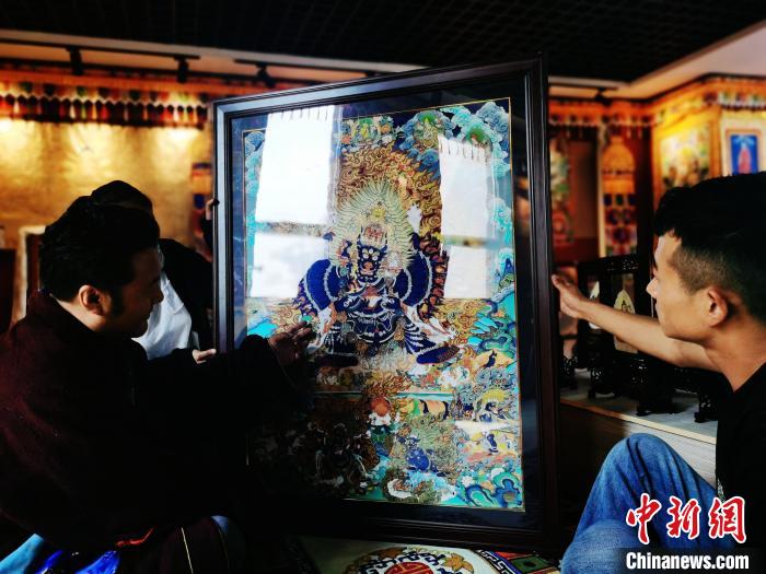 圖為久美尖措(左)與徒弟們展示唐卡作品?！?zhí)砀?攝