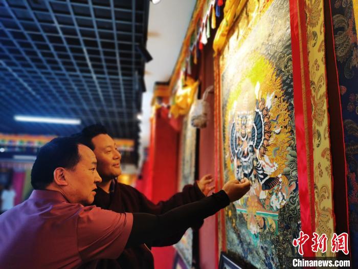 圖為久美尖措展示唐卡作品?！?zhí)砀?攝