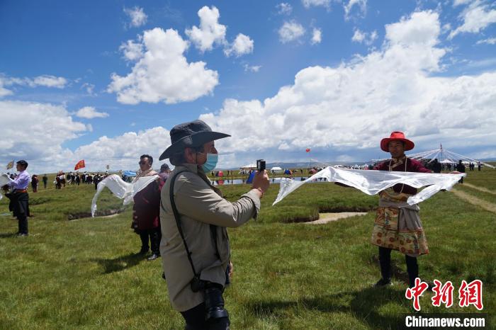 圖為一名外籍?dāng)z影師記錄當(dāng)?shù)夭刈鍤g迎儀式?！●R銘言 攝