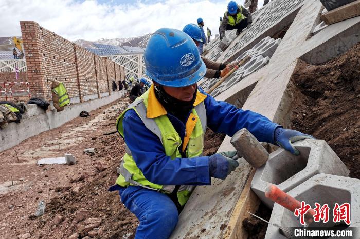 圖為光伏發(fā)電項(xiàng)目施工區(qū)工人在護(hù)坡鋪設(shè)空心磚?！±铍h 攝