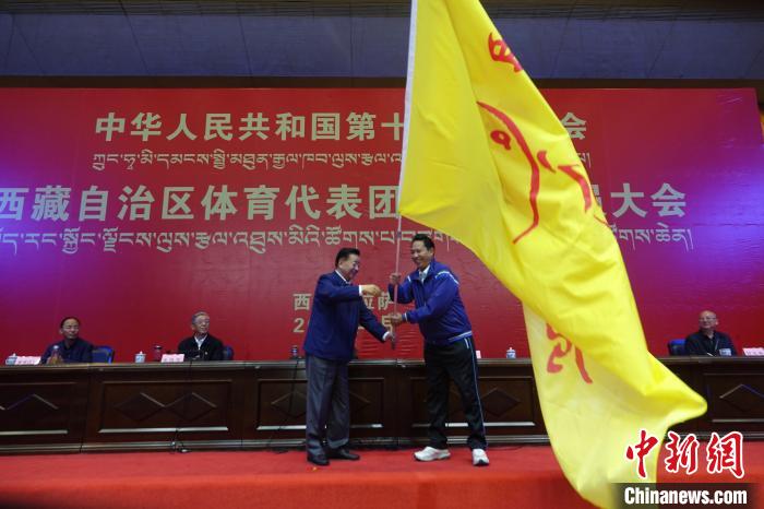 西藏自治區(qū)副主席甲熱·洛桑丹增授代表團團旗，西藏自治區(qū)體育局局長尼瑪次仁接旗。　冉文娟 攝