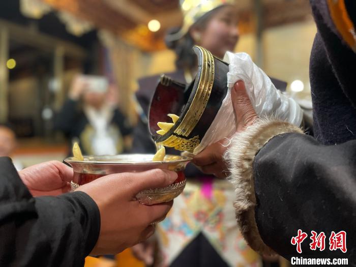 圖為主人在碗中斟滿青稞酒?！∪轿木?攝