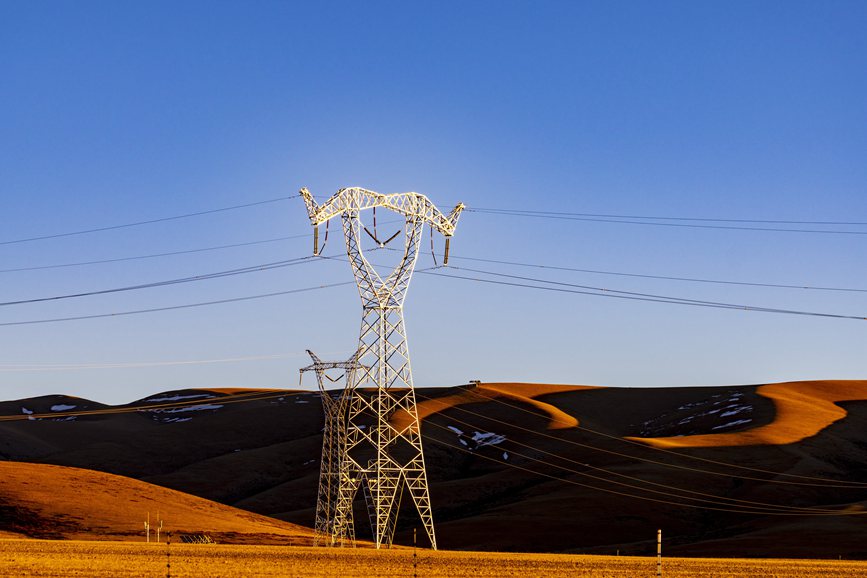 阿里地區(qū)的曠野上，電力鐵塔在夕陽下熠熠生輝。