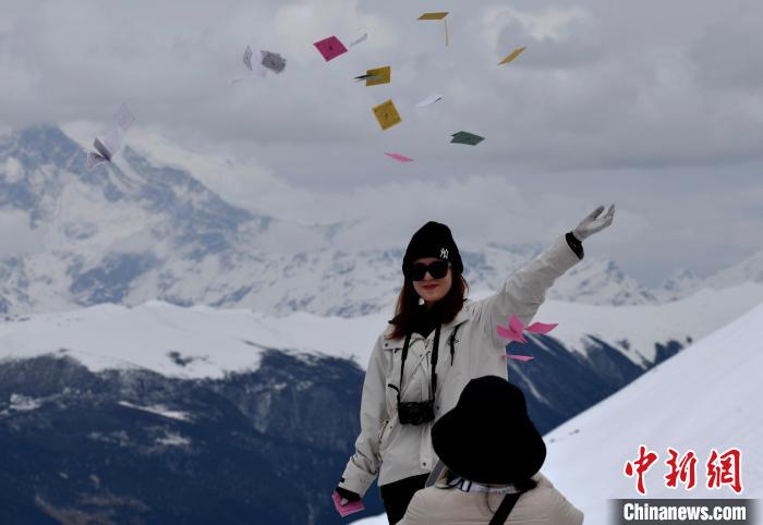 圖為5月14日，游客在西藏林芝色季拉山觀景臺拋灑“隆達(dá)”(風(fēng)馬旗，藏族民眾的一種祈福方式)?！±盍?攝