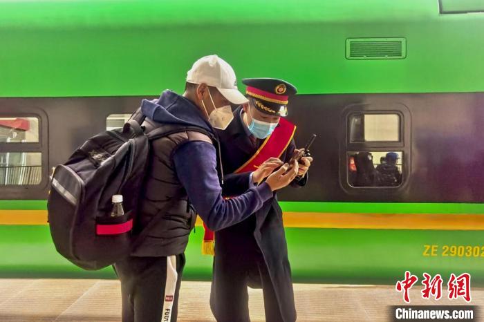 圖為日喀則火車站工作人員服務(wù)乘客?！《飞降?攝