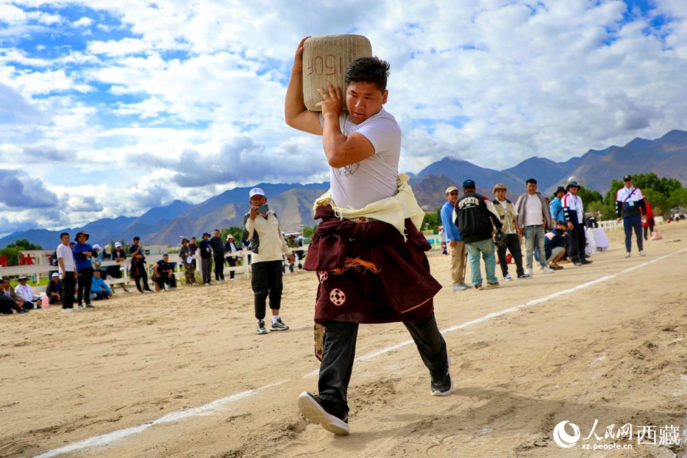 來自拉薩市當雄縣的牧民選手將一塊150斤重的石頭扛在肩上飛奔。