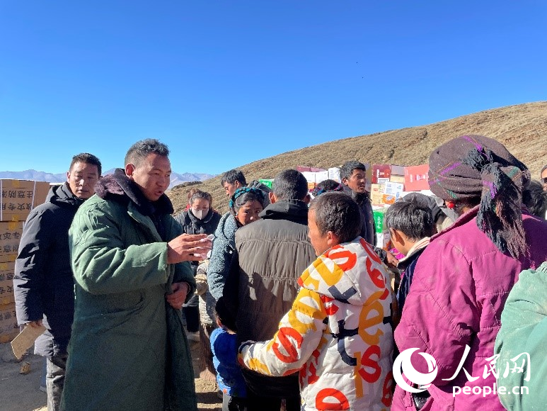 定日縣公安局干警頓珠次仁（左二）正在協(xié)助分發(fā)物資。人民網(wǎng)記者 郝潔攝