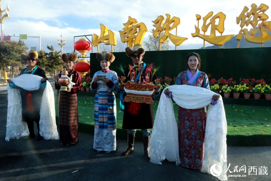 扎西曲登社區(qū)的居民在“山南歡迎您”標(biāo)志前，手持潔白哈達(dá)和切瑪，列隊(duì)迎接來自區(qū)內(nèi)外的游客，用最隆重的禮儀開啟一場(chǎng)沉浸式藏歷新年民俗體驗(yàn)之旅。人民網(wǎng)記者 吳雨仁攝