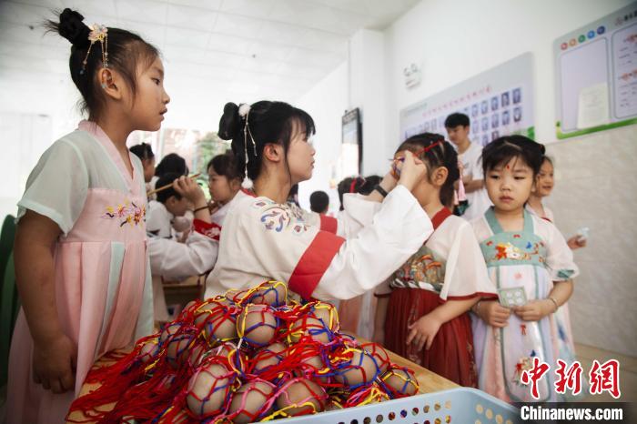 圖為幼兒園的老師們穿上漢服為小朋友們戴上彩蛋，寓意著幸福安康?！《^生 攝